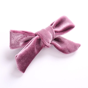 Detalle del suave tejido de terciopelo morado y diseño de lazo en la pinza para el cabello