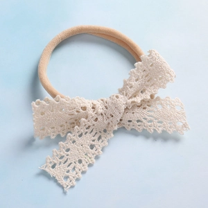 Dettaglio della fascia in pizzo beige con morbido elastico in nylon per neonate
