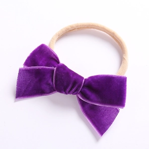 Detail einer weichen lila Samtschleife auf einem nahtlosen elastischen Baby Stirnband