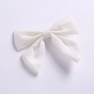 Détail de la pince à cheveux nœud papillon en coton blanc montrant la texture du tissu