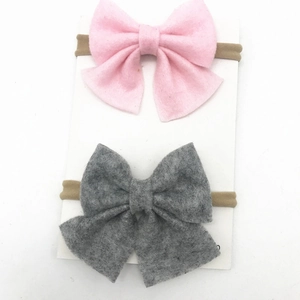 Detail of pink and grey felt bow headbands for infants on a white display card