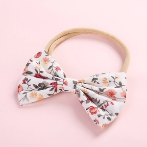 Détail d'un bandeau pour enfant avec nœud floral et ruban en nylon beige doux