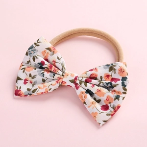 Détail d'un bandeau floral en coton pour bébé fille avec sangle en nylon nude extensible