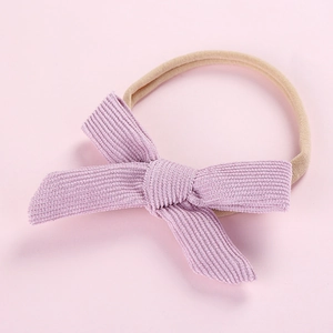 Close-up of light purple corduroy bow detail on a beige elastic nylon baby headband