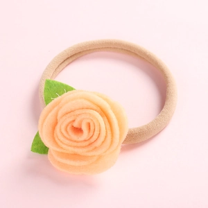 Détail d'une fleur de rose en feutre faite main sur un bandeau élastique pour bébés