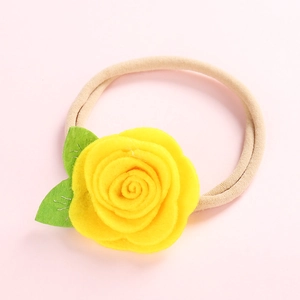 Détail d'une rose en tissu jaune et feuilles vertes sur un bandeau en nylon beige