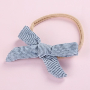 Close-up of light blue corduroy bow on nude elastic nylon headband for newborn infants