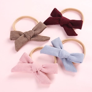 Set of four corduroy baby bow headbands in burgundy, brown, blue, and pink colors