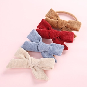 Detail showing set of four corduroy bow headbands in brown, red, blue and cream for infants
