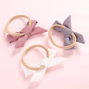 Close-up of three knitted newborn bow headbands in pink, grey and white ribbed fabric