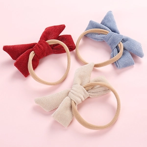 Detail view of newborn corduroy bow headbands in dark red, grey-blue and cream white
