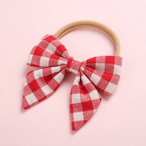 Gros plan détaillé d'un grand nœud à carreaux rouge et blanc sur bandeau bébé doux