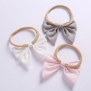 Detailed view of linen bow headbands in white, grey and pink with soft nylon bands