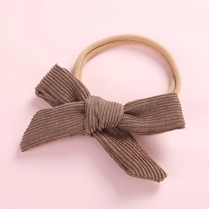Detailed view of brown corduroy bow newborn headband with soft nude nylon elastic band