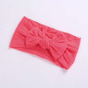 Detailed view of coral pink nylon baby headband with soft texture and large bow