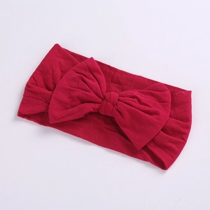 Close-up of a soft deep red knit nylon headband with a large bow for baby girls