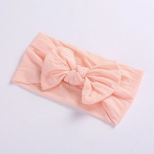 Detail shot of a soft pink nylon baby headband featuring a large stylish ribbed bow