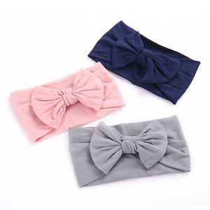 Detailed view of three soft nylon bow headbands in navy blue, light pink, and grey colors