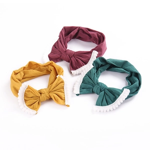 Three-piece baby nylon headband set with large bow and pompoms in yellow, red, and green