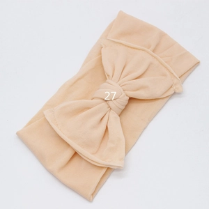 Detail of soft skin-tone baby headband featuring a large layered oversized bow