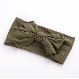 Gros plan sur un bandeau bébé en nylon vert olive avec un grand nœud papillon noué