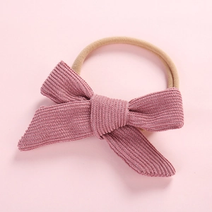 Close-up of baby headband featuring a dusty pink corduroy bow with high-elastic nylon band