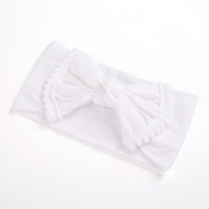 Detailed close-up of a white baby headband featuring a large pom-pom trimmed bow