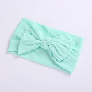 Detailed texture of baby nylon headband with large mint green bow on white background