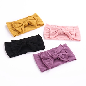 Detail view of four elastic soft knit baby headbands with oversized bows in various colors