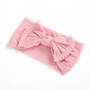 Close-up of pink baby nylon headband with large bow and soft pom pom lace edges