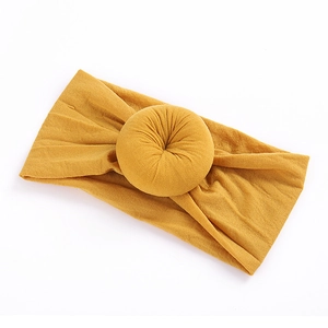 Detail of soft ribbed nylon baby headband with a mustard yellow donut knot decoration