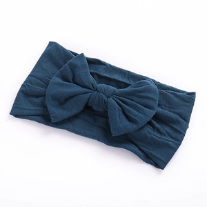 Close-up of navy blue nylon baby headband featuring a soft knitted texture and large bow