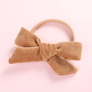 Detailed texture of caramel corduroy bow on a soft nude elastic nylon baby headband
