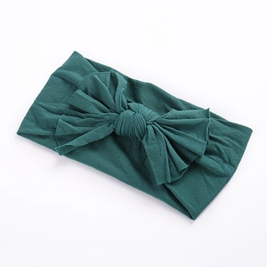 Texture détaillée du bandeau bébé en nylon vert foncé avec un double nœud papillon