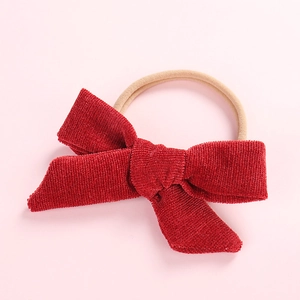 Detail of red corduroy bow on a soft nude nylon headband for newborn girls
