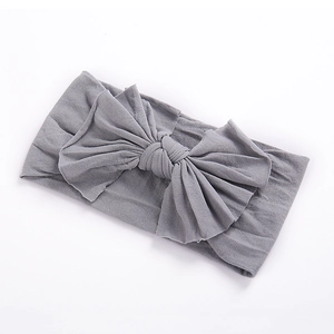 Détail d'un bandeau gris souple en nylon pour bébé avec un grand nœud sur fond blanc