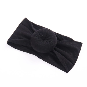 Close-up of soft black nylon baby headband featuring a donut knot design and stretchy fabric