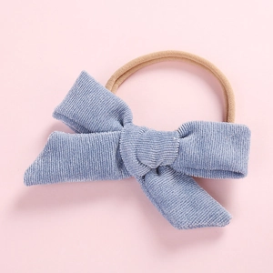 Detail of soft dusty blue corduroy bow on highly elastic nylon headband for babies
