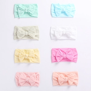 Flat lay of eight colorful soft nylon baby headbands with large bows in a neat row