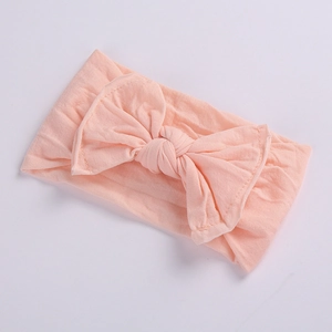 Close-up of baby pink elastic headband with a large knitted bow and soft fabric texture