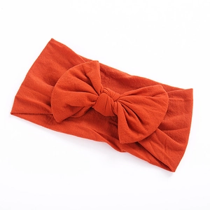 Close-up of soft nylon baby headband with a large bow in bright caramel color