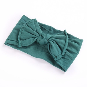 Detail of soft knit dark green bow headband showing flexible stretch fabric texture