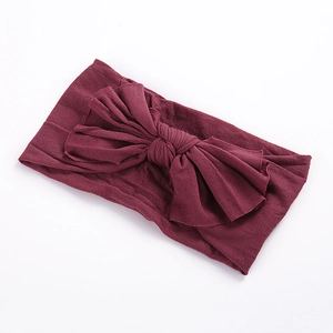 Gros plan détaillé du bandeau en nylon bordeaux avec un grand nœud tricoté pour filles