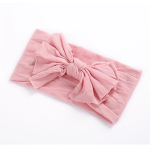 Gros plan d'un bandeau rose pour bébé en nylon souple avec un grand nœud papillon