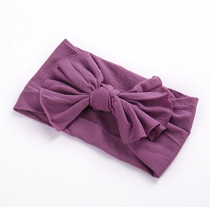 Vue détaillée du bandeau en nylon violet foncé avec un grand nœud fait main pour bébés