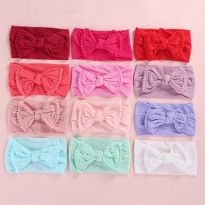 Detail of baby nylon headbands with large bows and pom-pom trim in twelve assorted colors