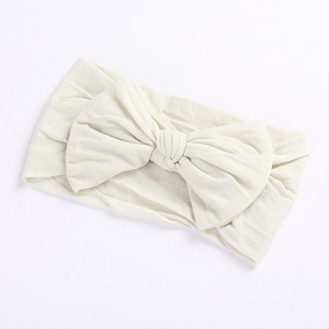 Detail showing the soft knit texture and large bow on a cream-colored baby headband