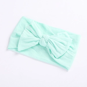 Close-up detail of soft mint green nylon baby headband with a large ribbed bow decoration