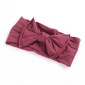 Detailed close-up of dark red soft elastic baby headband with a large bow decoration