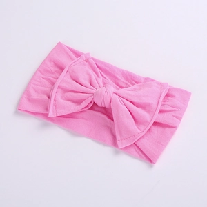 Close-up of soft pink knitted baby headband with a large decorative bow detail